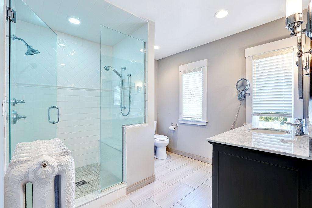 A sleek frameless shower glass partition in a modern bathroom, featuring clear tempered glass with a minimalist design, enhancing space and natural light.
