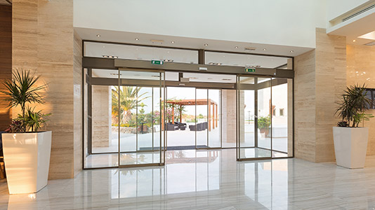 Automatic sliding glass door in a commercial building with motion sensors.
