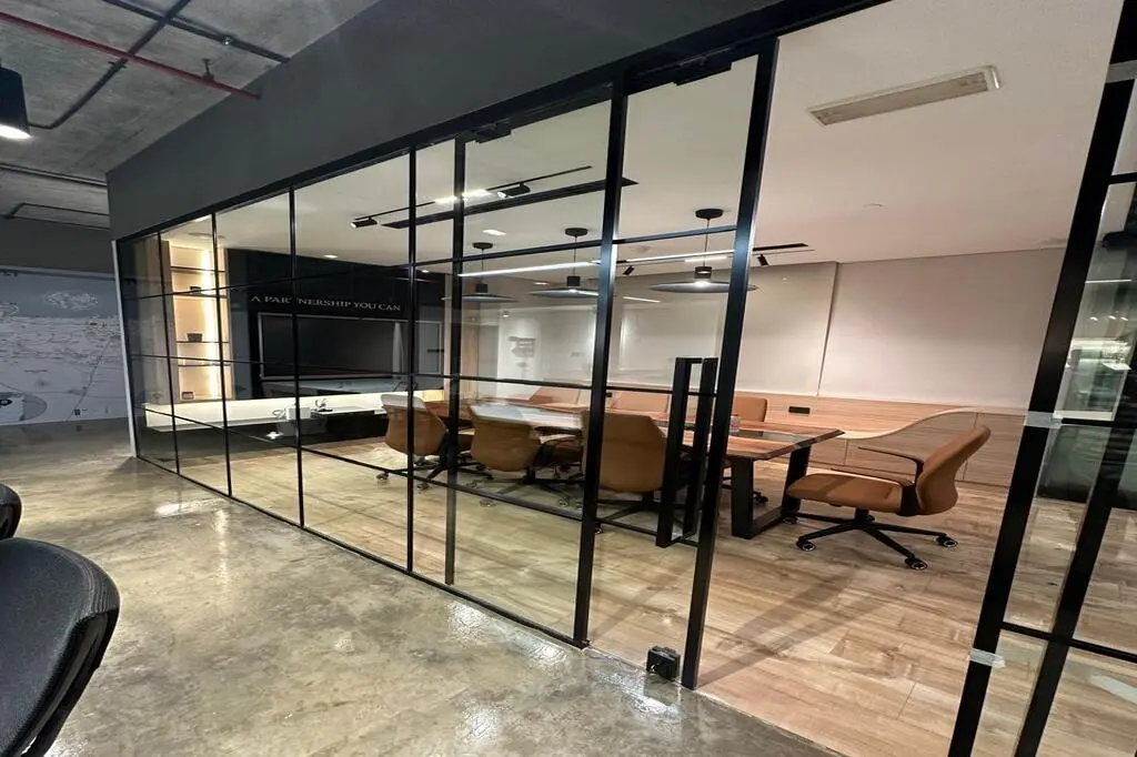 Modern glass partition wall in an office, featuring sleek frameless glass panels, enhancing natural light and creating a spacious, professional atmosphere.