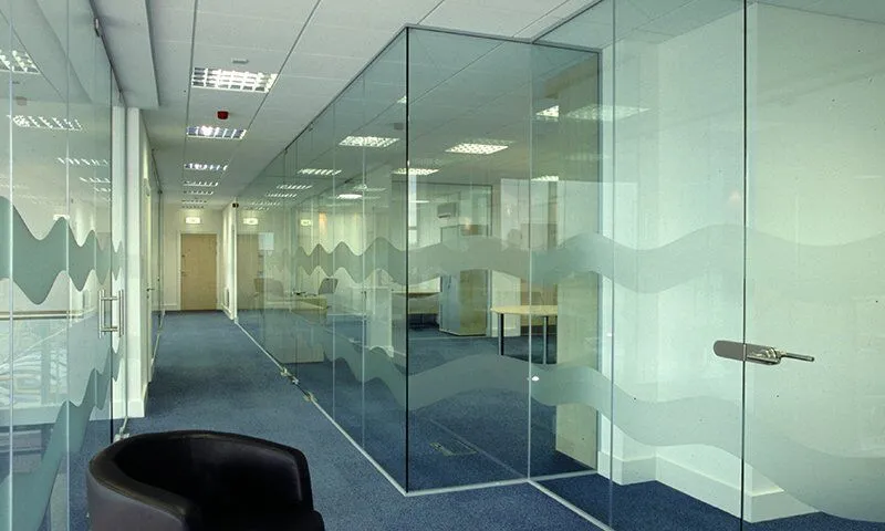 Frameless glass office partitions in a Dubai workspace with frosted manifestation banding